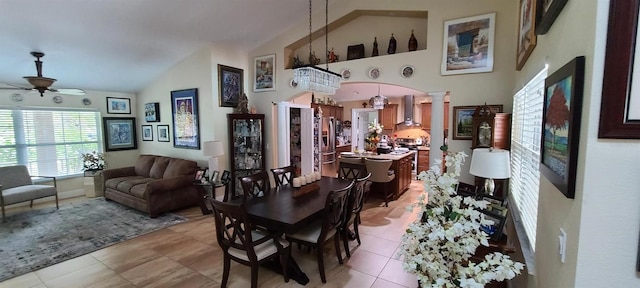 dining room with light tile patterned floors, high vaulted ceiling, arched walkways, a ceiling fan, and decorative columns