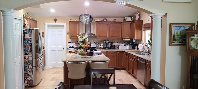 kitchen with appliances with stainless steel finishes, backsplash, wall chimney range hood, sink, and hanging light fixtures