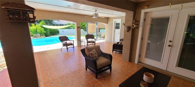 view of patio / terrace with french doors, a fenced in pool, and ceiling fan