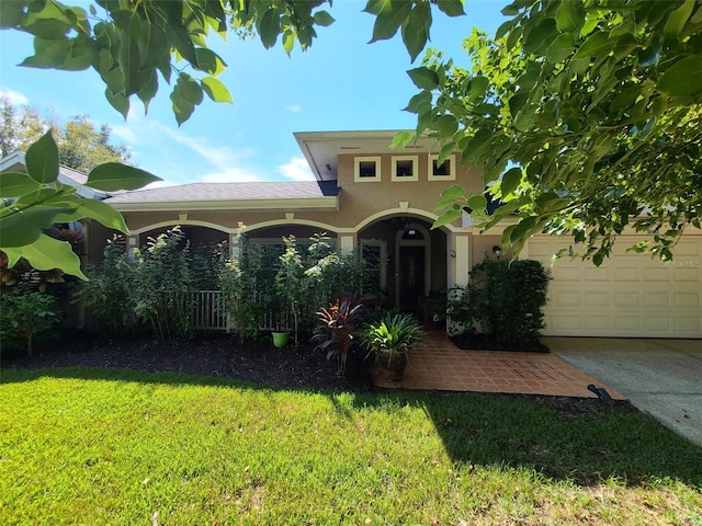 mediterranean / spanish house with an attached garage, driveway, a front lawn, and stucco siding