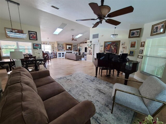 tiled living area with lofted ceiling with skylight, ceiling fan, and visible vents