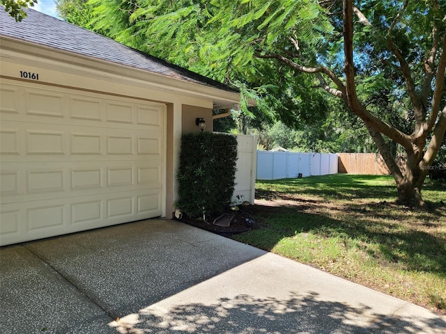 garage with concrete driveway and fence