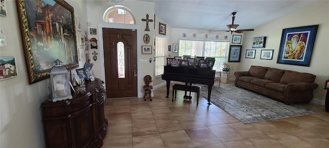 foyer with a ceiling fan, tile patterned flooring, vaulted ceiling, and baseboards