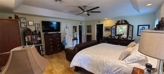 bedroom with a tray ceiling, visible vents, and a ceiling fan