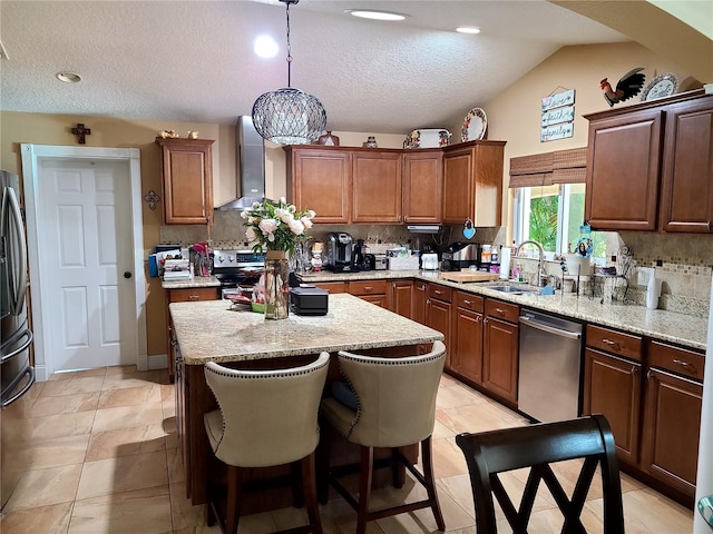 kitchen with a sink, a kitchen island, wall chimney range hood, tasteful backsplash, and appliances with stainless steel finishes