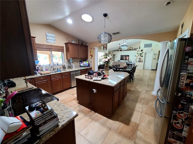 kitchen with a ceiling fan, ornate columns, appliances with stainless steel finishes, a kitchen island, and lofted ceiling