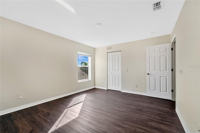 unfurnished bedroom with dark hardwood / wood-style floors and a closet