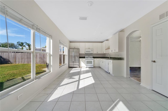 kitchen featuring white cabinetry, sink, ceiling fan, white appliances, and light tile patterned floors