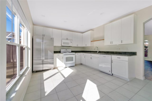 kitchen with light tile patterned floors, white appliances, white cabinetry, and sink