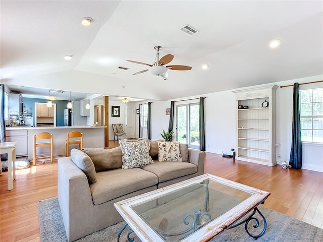 living room with ceiling fan, lofted ceiling, and light hardwood / wood-style floors