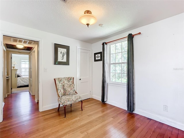 living area with wood-type flooring and a textured ceiling