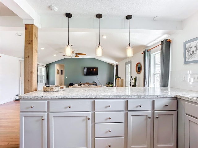 kitchen with vaulted ceiling with beams, gray cabinetry, hanging light fixtures, hardwood / wood-style flooring, and kitchen peninsula