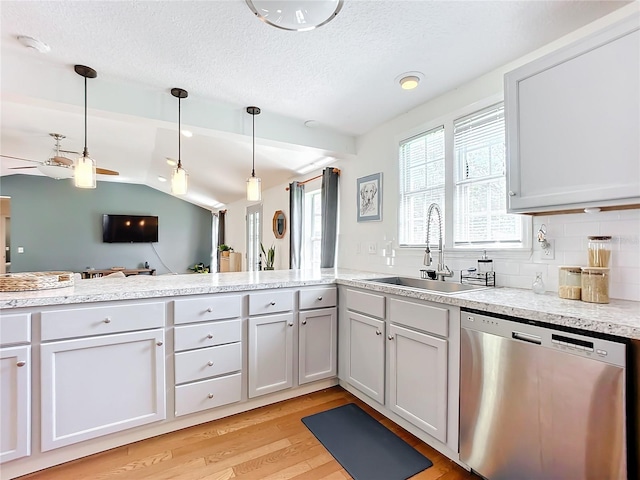 kitchen with pendant lighting, sink, decorative backsplash, stainless steel dishwasher, and light hardwood / wood-style flooring