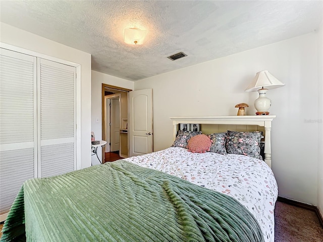 bedroom featuring a closet, dark carpet, and a textured ceiling