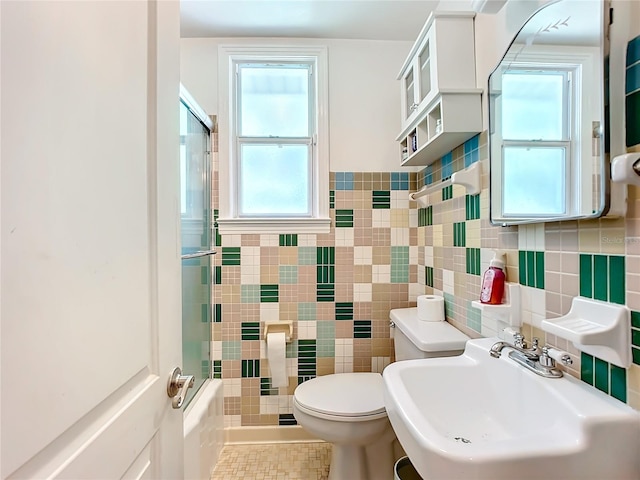 full bathroom featuring toilet, sink, tile walls, and combined bath / shower with glass door