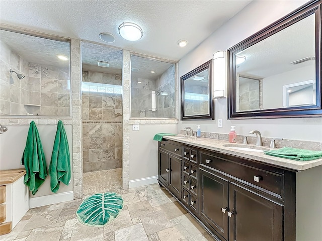 bathroom with vanity, a textured ceiling, and a tile shower