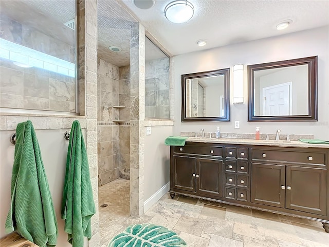 bathroom featuring vanity, a textured ceiling, and tiled shower