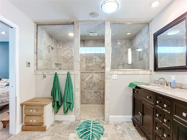 bathroom with vanity, a textured ceiling, and a tile shower