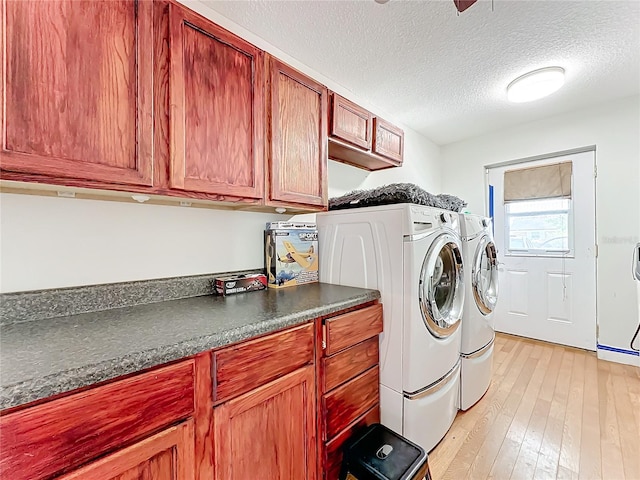 washroom featuring cabinets, a textured ceiling, washer and clothes dryer, and light hardwood / wood-style flooring