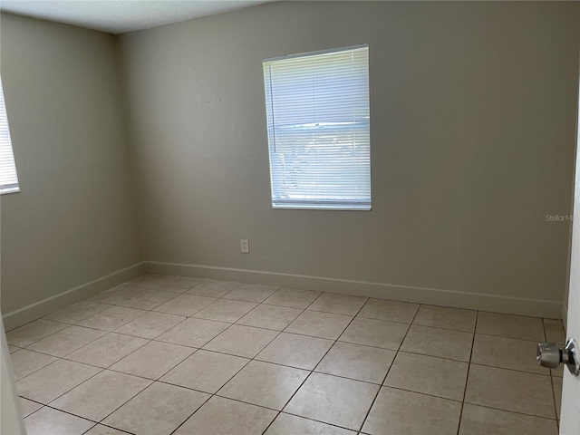 tiled empty room with a textured ceiling