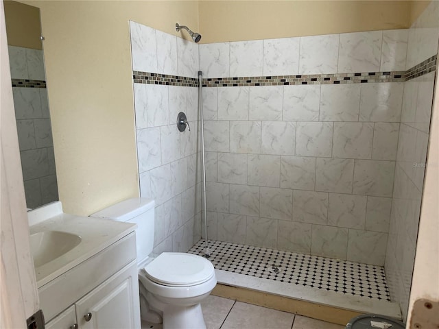 bathroom featuring vanity, tile patterned flooring, toilet, and tiled shower