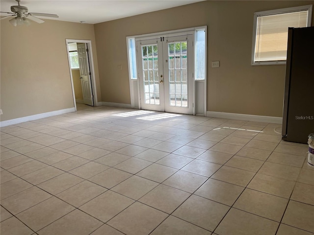 tiled empty room featuring ceiling fan and french doors