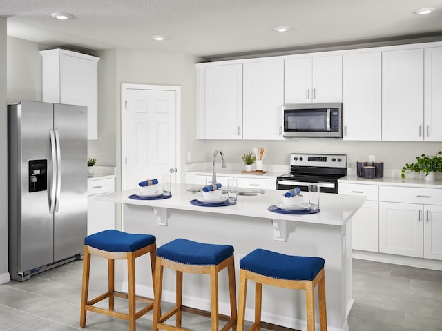 kitchen with a center island with sink, appliances with stainless steel finishes, a textured ceiling, and white cabinetry