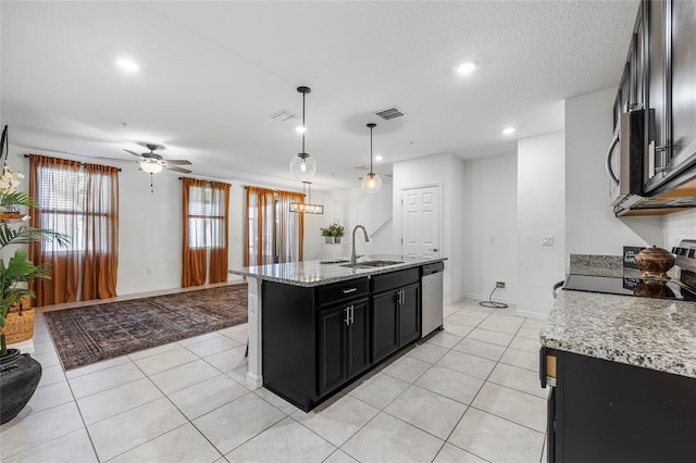 kitchen with pendant lighting, an island with sink, stainless steel appliances, light stone countertops, and ceiling fan