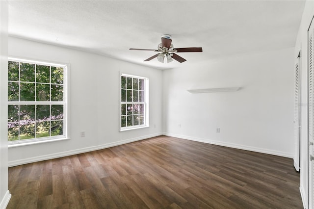 unfurnished room with a wealth of natural light, ceiling fan, and dark hardwood / wood-style flooring