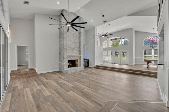 unfurnished living room with high vaulted ceiling, a stone fireplace, ceiling fan, light hardwood / wood-style flooring, and pool table