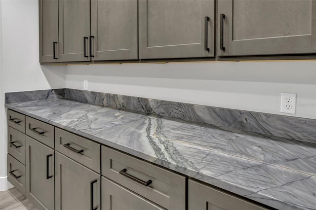 kitchen with gray cabinetry, light hardwood / wood-style floors, and light stone counters