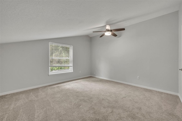 carpeted spare room with ceiling fan, a textured ceiling, and vaulted ceiling