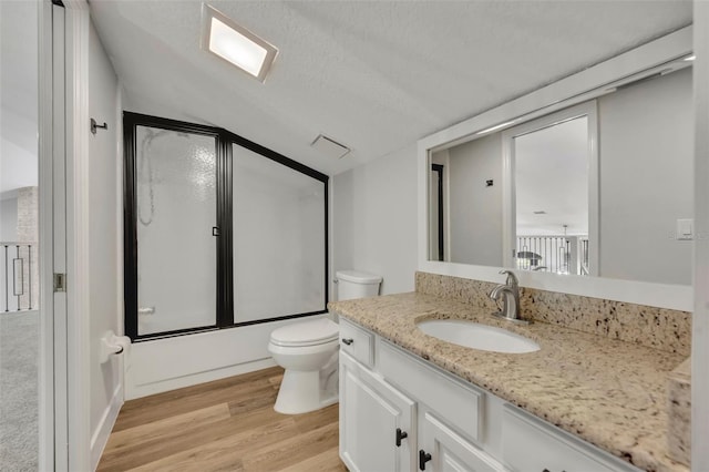 full bathroom with vanity, wood-type flooring, lofted ceiling, shower / bath combination with glass door, and toilet