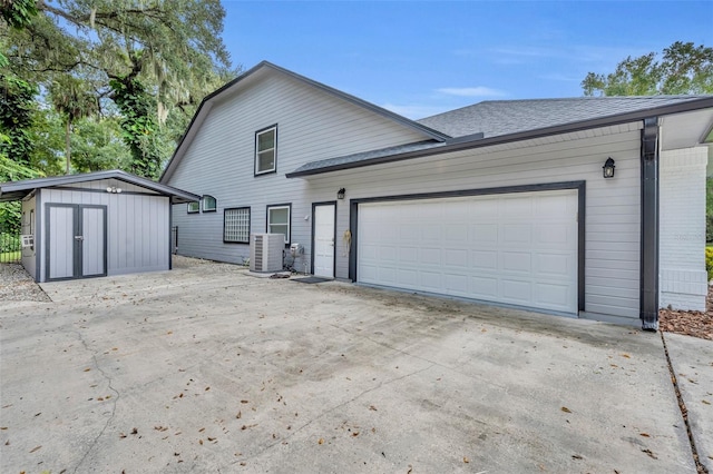 exterior space with cooling unit, a storage unit, and a garage