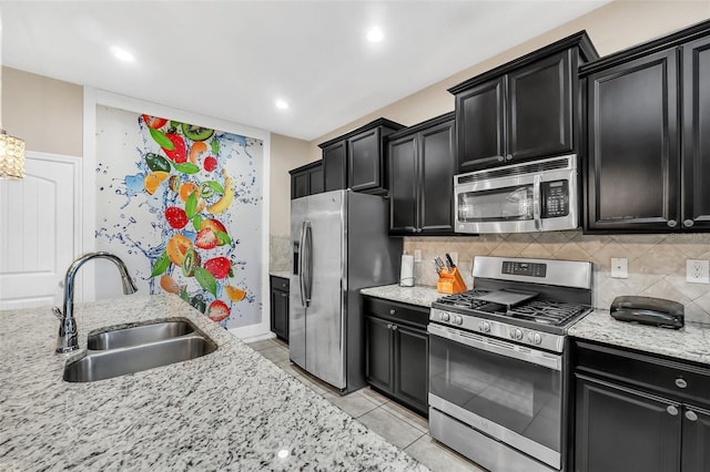 kitchen with decorative backsplash, sink, stainless steel appliances, and light stone countertops