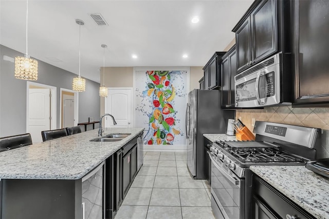 kitchen with a kitchen breakfast bar, an island with sink, pendant lighting, stainless steel appliances, and sink