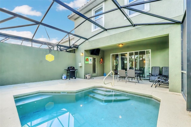 view of pool with glass enclosure and a patio area