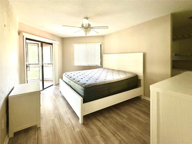 bedroom with a textured ceiling, hardwood / wood-style floors, and ceiling fan