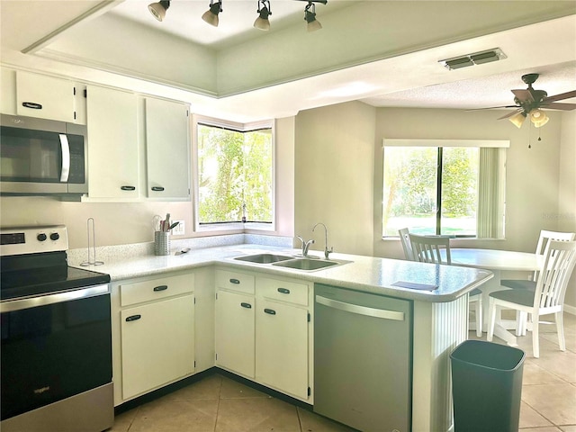 kitchen with ceiling fan, sink, kitchen peninsula, white cabinetry, and stainless steel appliances