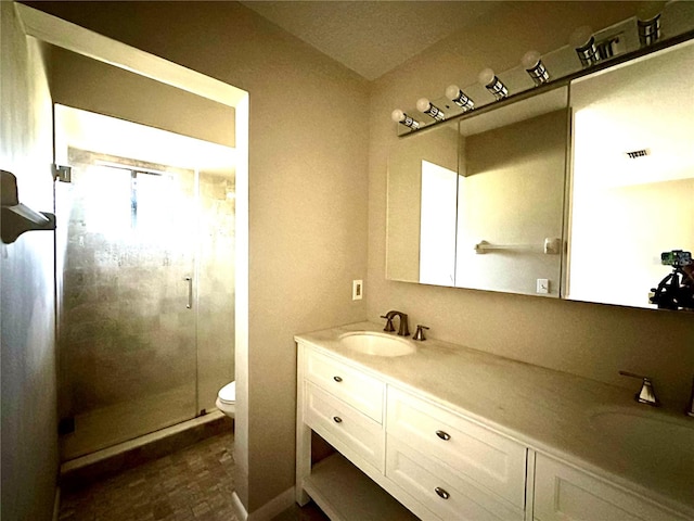 bathroom with walk in shower, vanity, and toilet