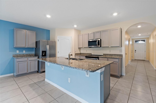 kitchen with gray cabinets, sink, an island with sink, a breakfast bar area, and appliances with stainless steel finishes