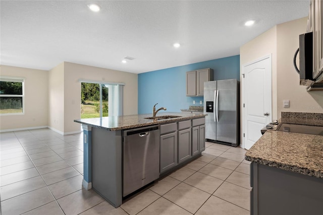 kitchen featuring light tile patterned flooring, sink, an island with sink, gray cabinetry, and appliances with stainless steel finishes