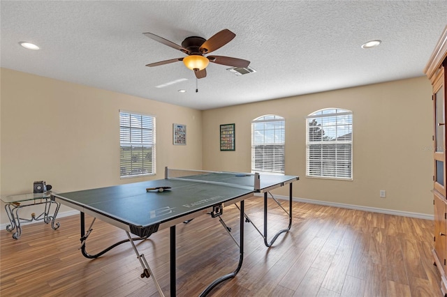 rec room with a textured ceiling, light hardwood / wood-style flooring, and ceiling fan