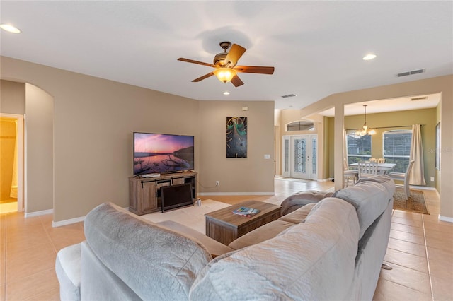 living room featuring ceiling fan with notable chandelier and light tile patterned floors