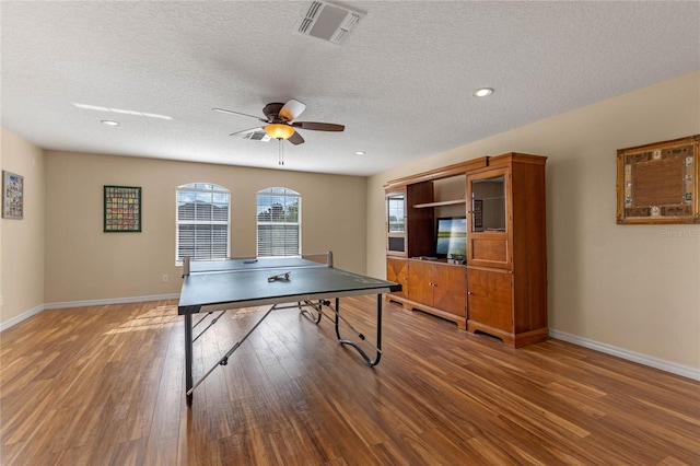 recreation room featuring hardwood / wood-style flooring, ceiling fan, and a textured ceiling