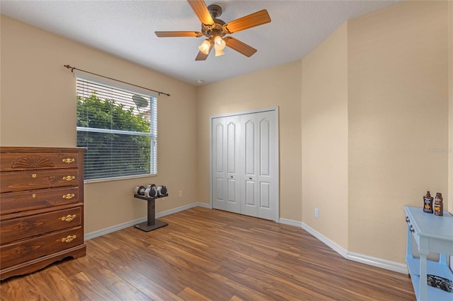 unfurnished bedroom featuring hardwood / wood-style flooring, ceiling fan, a textured ceiling, and a closet