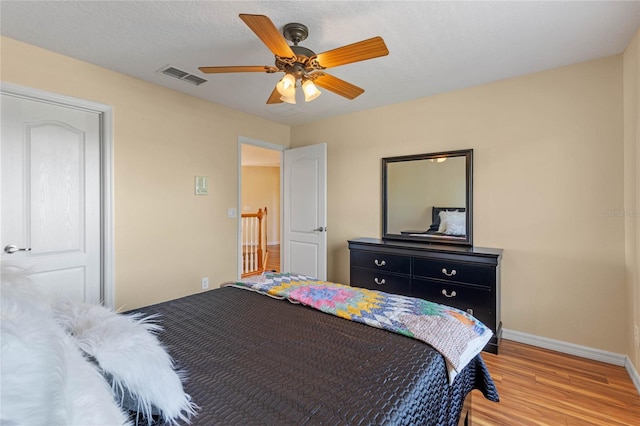 bedroom featuring ceiling fan, light hardwood / wood-style floors, and a textured ceiling