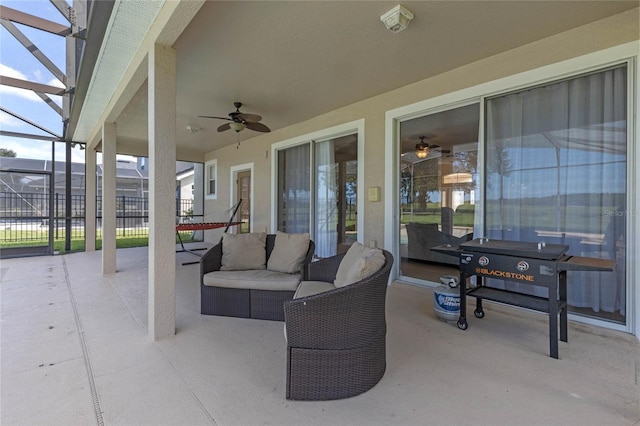 view of patio with outdoor lounge area, glass enclosure, and ceiling fan