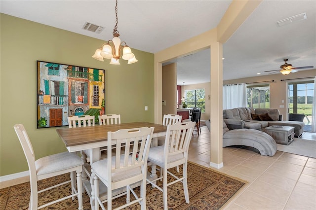 tiled dining room with ceiling fan with notable chandelier and a healthy amount of sunlight