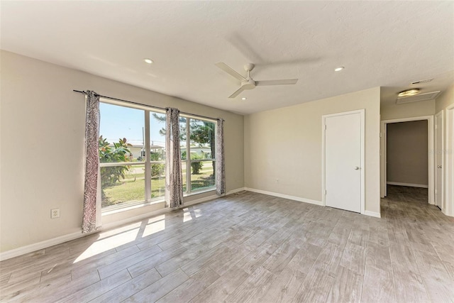 empty room with ceiling fan, a textured ceiling, and light wood-type flooring